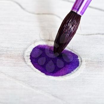 painting violet ornament on silk canvas with brush close up