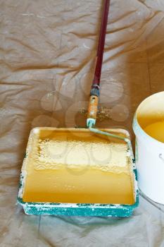 plastic paint tray with yellow emulsion paint and painter roller brush
