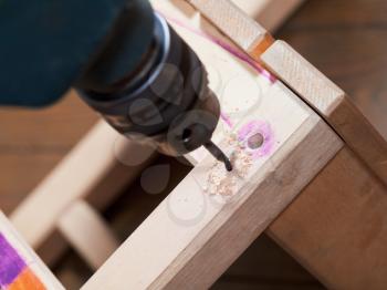 repairing of wooden chair with drill close up