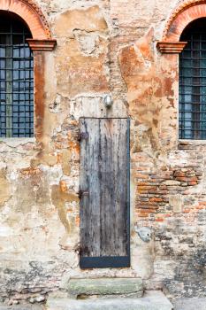 old wooden door in shabby brick wall of medieval house in Bologna, Italy