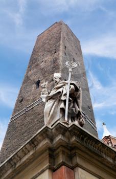 garisenda tower and the statue of Saint Petronius under blue sky in Bologna, Italy