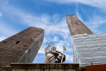 Two towers and the statue of Saint Petronius under blue sky in Bologna, Italy
