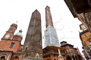 palace and two towers and statue of Saint Petronius under grey sky in Bologna, Italy