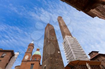 palace and two towers and statue of Saint Petronius under blue sky in Bologna, Italy