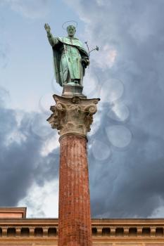 statue and column of Saint Dominic near Basilica of San Domenico with gray clouds, Bologna, Italy
