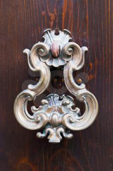 old bronze door handle on brown wooden urban door
