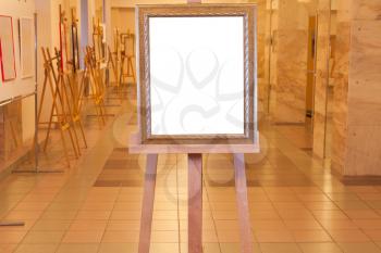 wooden picture frame with white cut out canvas on easel in art gallery