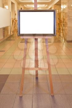 brown wood picture frame with white cut out canvas on easel in art gallery hall