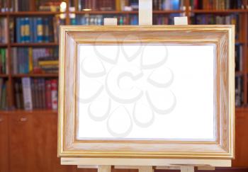 white canvas of wood picture frame on easel with clipping path and home library on background