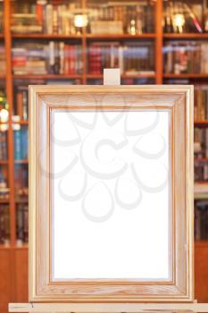 white canvas of wide picture frame on easel with clipping path and home library on background