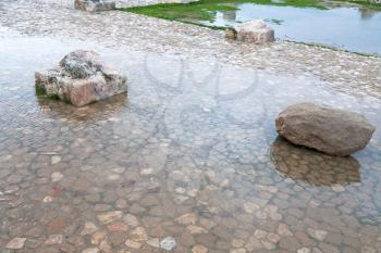 stone and column ruin in puddle in rainy day