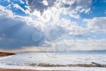 sunbeams though dark blue clouds above Dead Sea