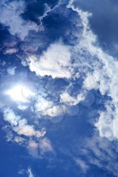 sun and cumulus clouds in dark blue summer sky