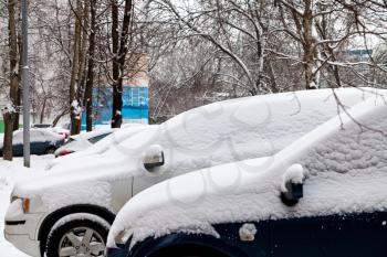 cars covered with snow on parking in winter day Moscow, Russia