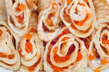 several pancakes rolls with red caviar close up