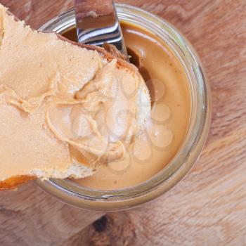 toast with peanut butter and knife in a glass jar on wooden table