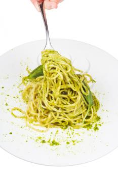 eating spaghetti mixed with fresh pesto from white plate isolated on white background