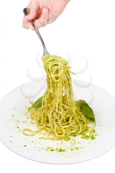 eating spaghetti mixed with pesto from white plate isolated on white background