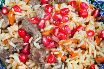 background from asian plov with pomegranate seeds and meat close up