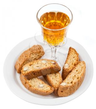 crystal glass with sweet white wine and italian almond cantuccini on saucer isolated on white background