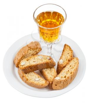 wineglass with sweet white wine and italian almond cantuccini on saucer isolated on white background