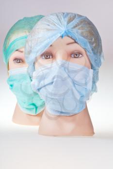two women's dummy doctor heads wearing textile surgical cap and medical protective mask