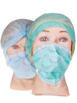 two female dummy doctor heads wearing textile surgical cap and medical protective mask isolated on white background