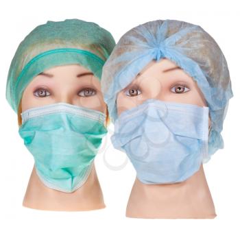 two female dummy doctor heads wearing textile surgical cap and medical protective mask isolated on white background