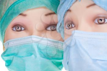 two female dummy doctor heads wearing textile surgical cap and medical protective mask close up