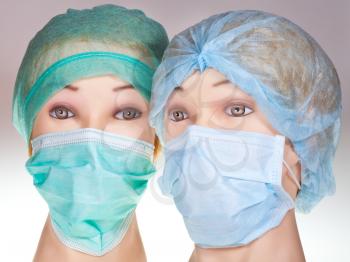 two female dummy doctor heads wearing textile surgical cap and medical protective mask
