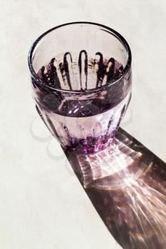 Purple faceted glass with clear water lit by the sun light