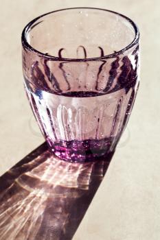 Purple faceted glass with potable water lit by the sun light
