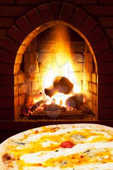 italian pizza quatro formaggi and open fire in wood burning stove