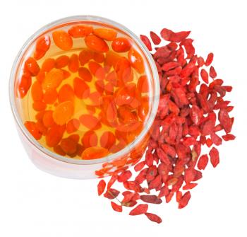 preparing of goji berry tincture - top view of glass with goji berries infusion and heap of dried fruits isolated on white background