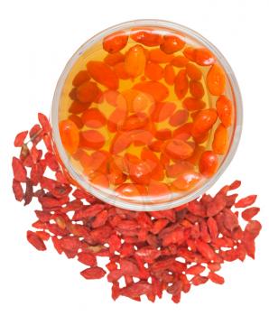 preparing of goji berry tincture - above view of glass with goji berries infusion and dried fruits isolated on white background