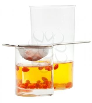 cooking of goji berry tincture - side view of pot and glass with goji berries infusion isolated on white background