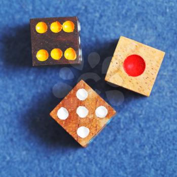 top view of three wooden gambling dices on blue cloth of gaming table