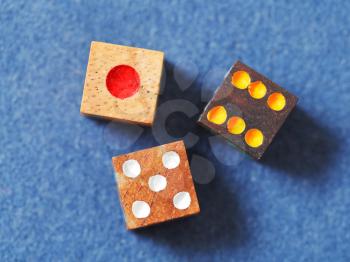 three wooden gambling dices on blue cloth of gaming table close up