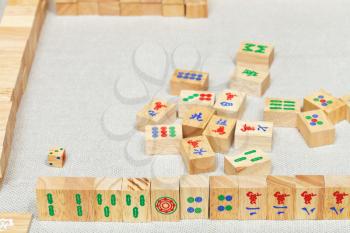 player hand from wooden tiles in mahjong game on textile table