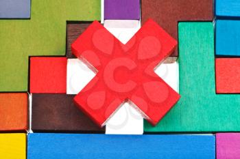 cross shaped block on wooden multicoloured puzzle isolated on white background