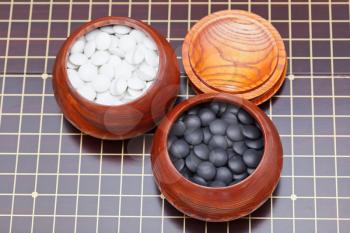 above view of black and white go game stones in wooden bowl