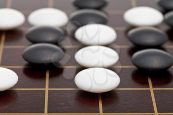 position of stones during go game playing on wooden goban close up