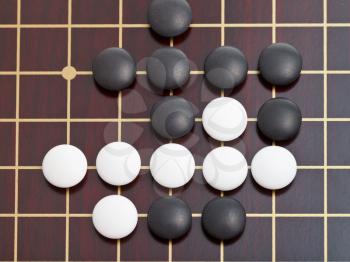 top view of stones during go game playing on wooden goban