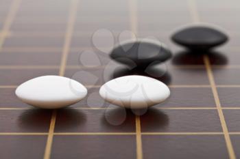 position of few stones during go game playing on wooden board close up