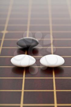 three stones during go game playing on wooden board close up