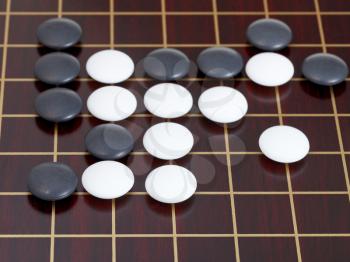 many black and white stones during go game playing on wooden board close up