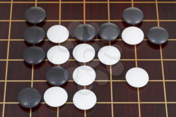 top view of many black and white stones during go game playing on goban close up