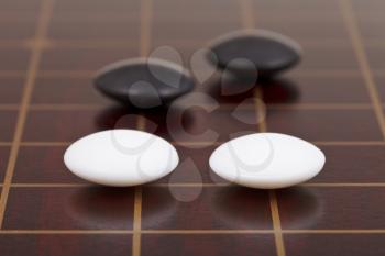 four stones during go game playing on goban close up
