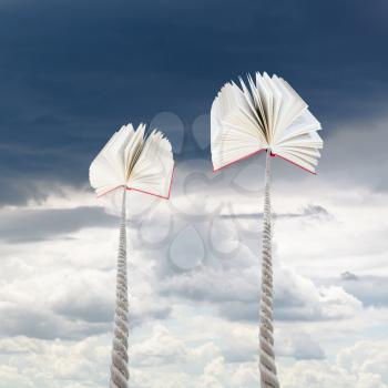 two books tied on ropes soars into rainy sky