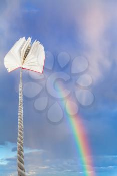 book tied on cord soars into blue sky with rainbow